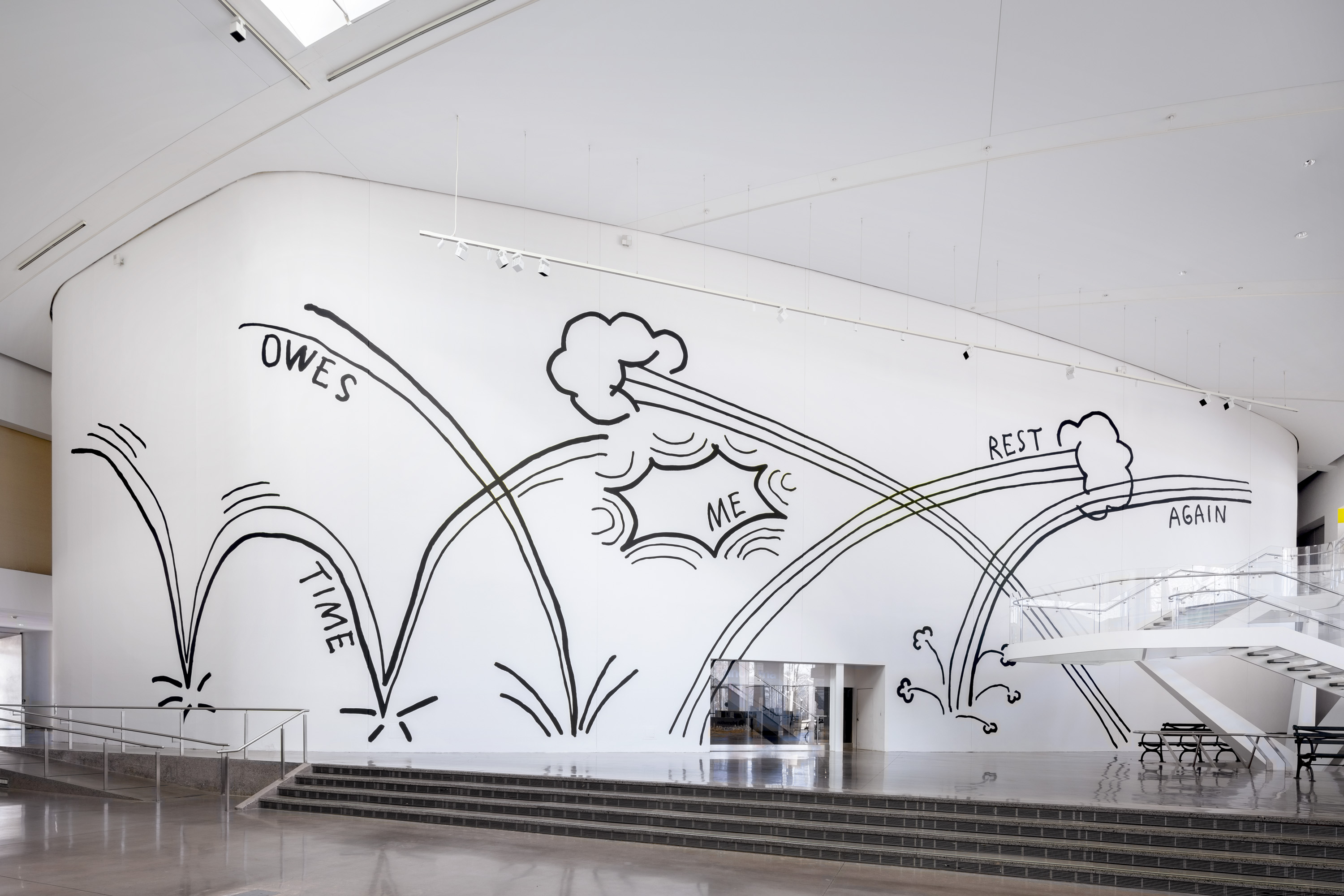 Large mural on a white wall with thick black lines, by Christine Sun Kim "Time Owes Me Rest Again" in the main lobby area of Queens Museum.