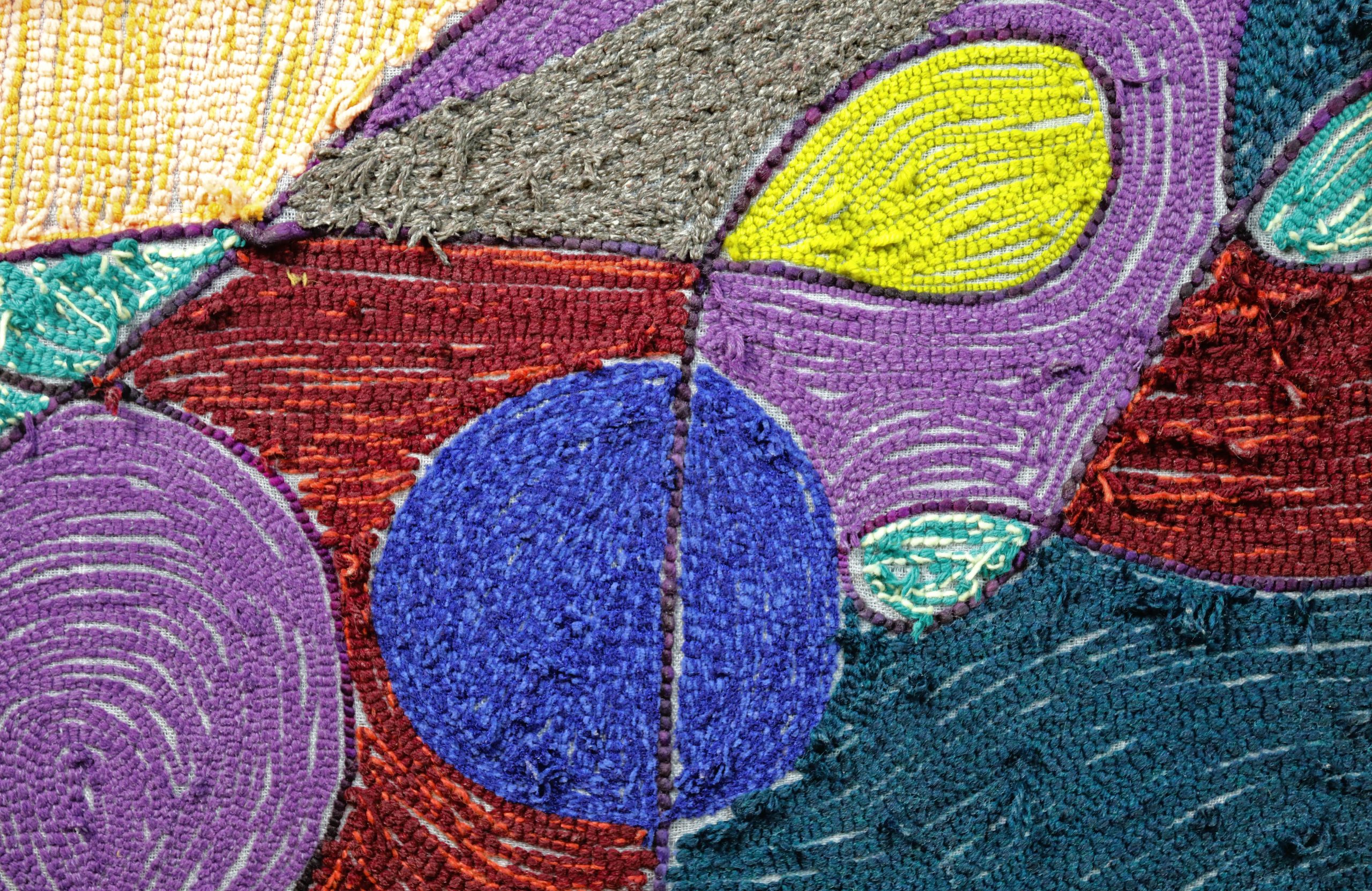 A zoomed-in detail of the back of a soft painting with a purple running line tracing some looped shapes. In the detail view, a large blue circle and smaller lime green oval are most prominent, with purple, gray and dark green in the background.