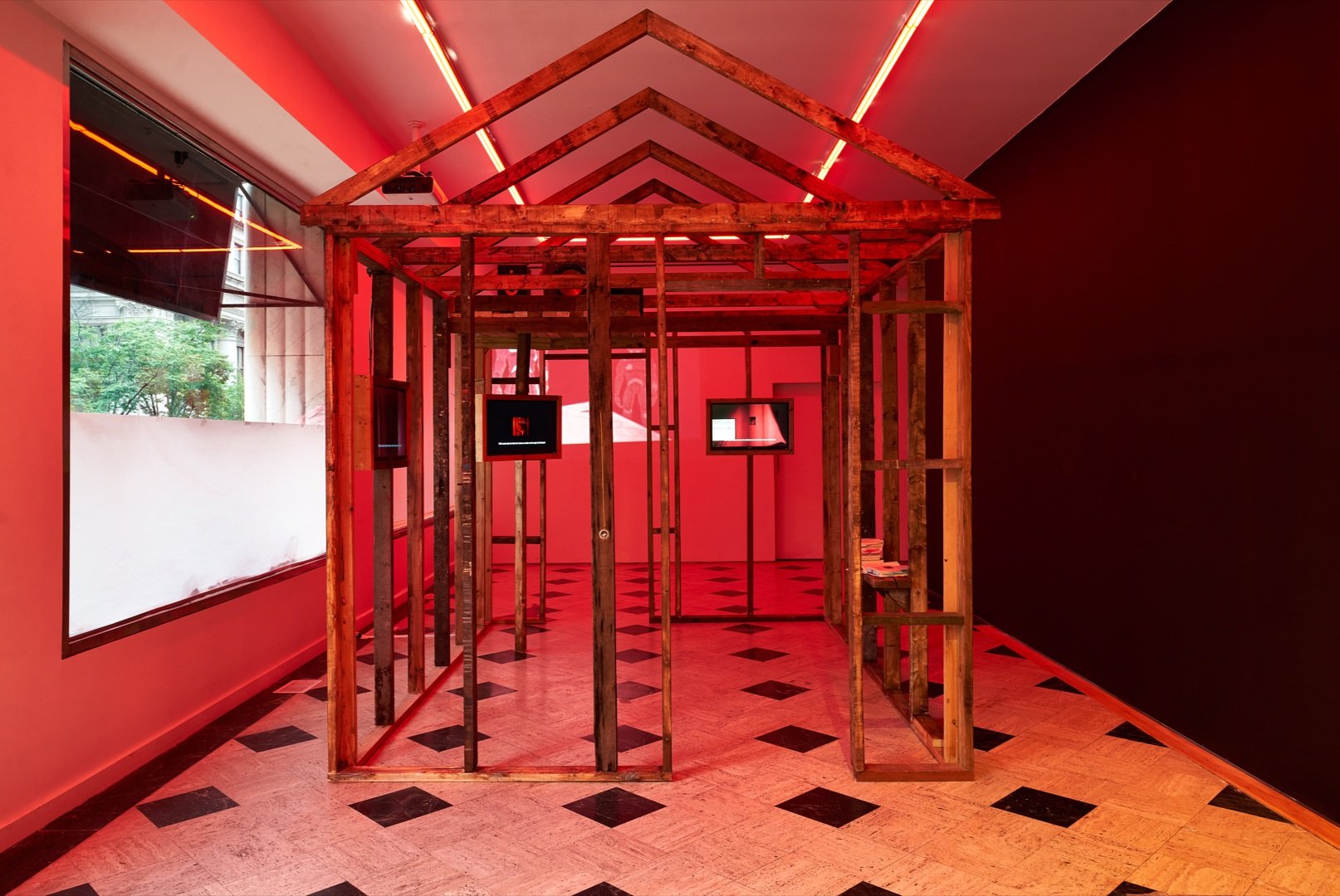 a wooden frame of a large house, in a room lit by red lights.